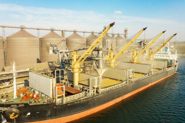 Cargo ship loading grain at port with storage silos